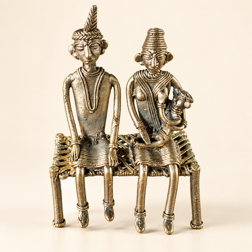 An antique-style metal figurine depicting a seated couple on a woven chair, crafted in a textured metallic finish with warm bronze and silver tones, set against a plain beige background.