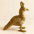 Dokra-inspired golden peacock figurine with intricate feather patterns and traditional detailing, displayed against a warm cream background by Kalavan.